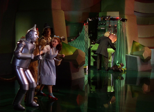 Personajes de la obra Mago de Oz descubriendo algo mago detrás de la cortina.